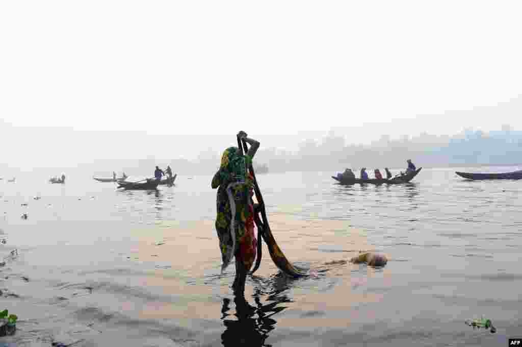 یکی از شهروندان داکا در بنگلادش در حال شستن لباس در رودخانه