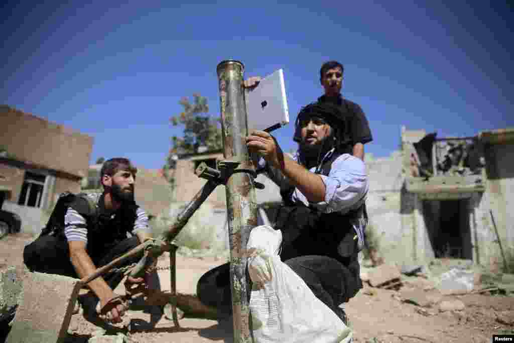 A member of the Ansar Dimachk Brigade, part of the rebel Free Syrian Army battling forces loyal to Syrian leader Bashar al-Assad, uses an iPad during preparations to fire a homemade mortar at one of the battle front in Damascus. (Reuters/Mohamed Abdullah)