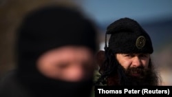 Bratislav Zhivkoviq (R), anëtar i grupit paramilitar serb dhe një anëtar i njësisë lokale të vetëmbrojtjes duke drejtuar një pikë kontrolli në autostradën midis Simferopolit dhe Sevastopolit në gadishullin e Krimesë, 13 mars 2014.