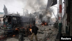 A policeman calls for help as he stands near a burning site after a bomb blast in Quetta on March 14, 2014.
