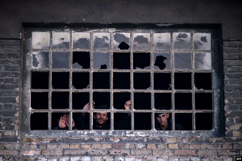 Migrants look out from a window in a makeshift shelter at an abandoned warehouse in Belgrade, Serbia. (AFP/Andrej Isakovic)