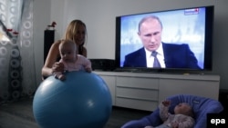 Женщина с детьми у телевизора, по которому показывают "прямую линию" с президентом России Владимиром Путиным. Москва. 16 апреля 2015 года.