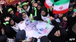 Iranian women hold an anti-American poster bearing a cartoon of U.S. President Barack Obama outside the former U.S. Embassy in Tehran on November 2.