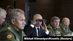 Russian President Vladimir Putin uses binoculars to watch the Zapad 2017 war games, held by Russian and Belarusian forces, with Defense Minister Sergei Shoigu (left).