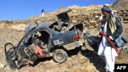 FILE: Villagers stand near a destroyed vehicle following a roadside explosion in the eastern province of Nangarhar.