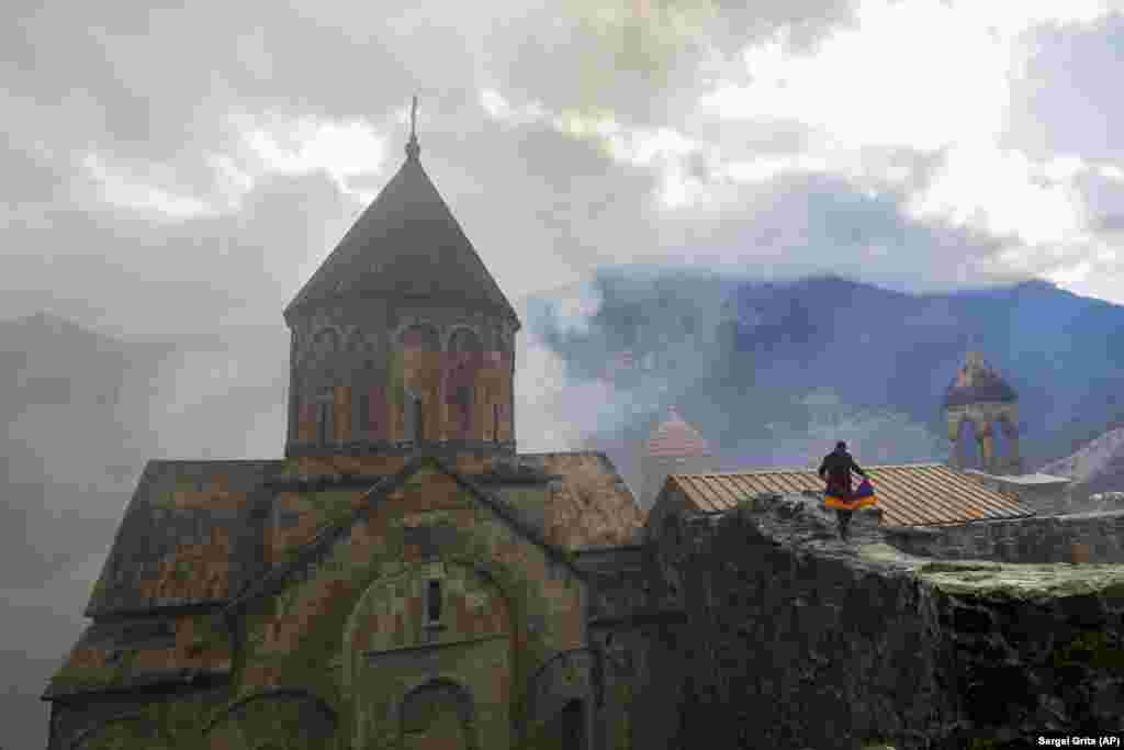 Мужчина с армянским национальным флагом посещает монастырь Дадиванк XII-XIII веков на окраине Кельбаджара в Нагорном Карабахе, 13 ноября 2020 года. Согласно договору о перемирии, эту территорию стал контролировать Азербайджан