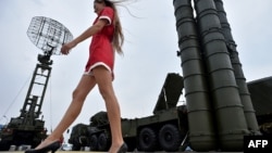 A woman walks past S-400 air-defense systems at a military exhibition outside Moscow.