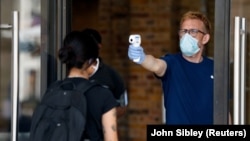  اندازه‌گیری دمای بدن یک مشتری به هنگام ورود به فروشگاه اپل در لندن