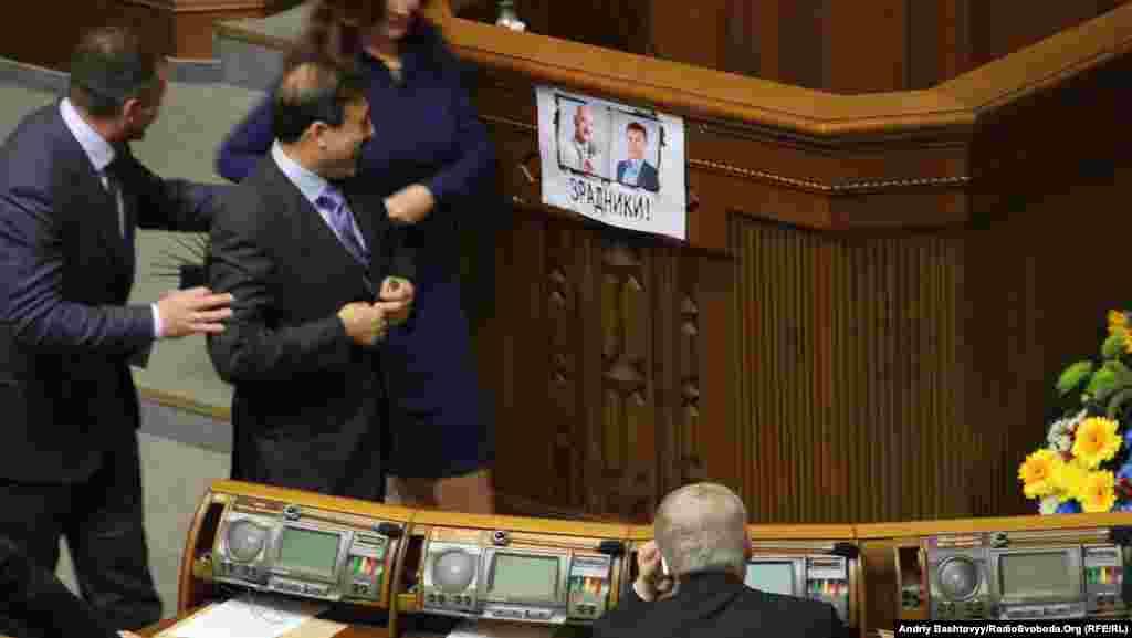The inaugural session even came with its own fight card taped to the rostrum, in this case accusing father-and-son opposition lawmakers Andriy and Oleksandr Tabalov of planning to defect to the ranks of the ruling Party of Regions. Both Tabalovs were pushed from the chamber before they could be administered the parliamentary oath.