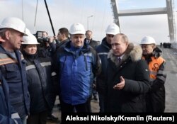 Russian President Vladimir Putin (second right) inspects a completed section of a bridge over the Kerch Strait that is meant to link Crimea to Russia.