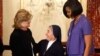 U.S. Secretary of State Hillary Clinton (left) presents the award to Sister Marie Claude Naddaf of Syria as first lady Michelle Obama looks on.