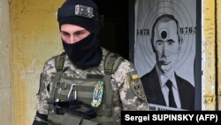 Боец Территориальной обороны Украины и мишень с изображением президента России Владимира Путина