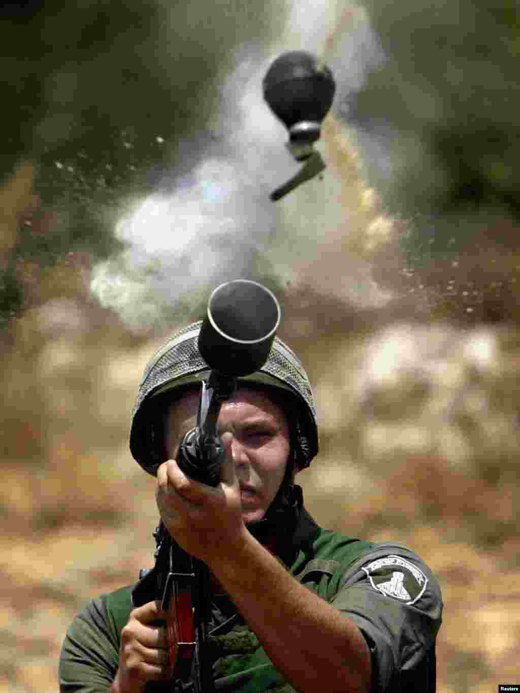 An Israeli border policeman fires teargas canister during a protest by Palestinians against the construction of the controversial Israeli security barrier in the West Bank village of Az-Zawiya June 20, 2004. REUTERS/Goran Tomasevic