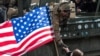 A woman waves a U.S. flag as she welcomes a soldier of the convoy known as the &quot;Dragoon Ride.&quot;