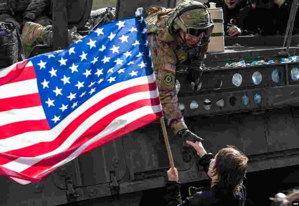 A woman waves a U.S. flag as she welcomes a soldier of the convoy known as the &quot;Dragoon Ride.&quot;