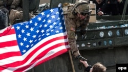 Женщина с флагом США приветствует американских солдат в Праге. 30 марта 2015 года.