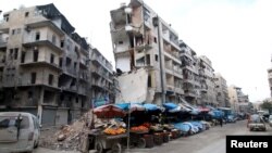 Syria -- Stalls are seen on a street beside damaged buildings in the rebel held al-Shaar neighborhood of Aleppo, February 10, 2016