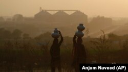 Pakistani nomad women carry water to their houses in a hazy evening on the outskirts of Islamabad. (file photo)