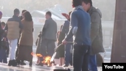 A screengrab from a video circulated on the Internet that appears to show two men in Bishkek roasting potatoes on the eternal flame at the city's memorial to Kyrgyzstan's World War II dead.