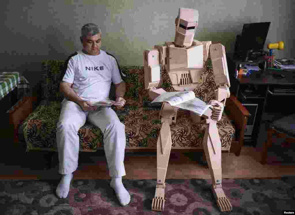 Ukraine's Dmitry Balandin poses with his wooden model called Cylon in his flat in Zaporizhzhya. It took Balandin six months to build the model from 500 parts. Balandin says he does not use blueprints and designs the parts as he works on them. He says he would love to build metal models but that it is impossible to do so in his small apartment. He plays with Cylon as a child would play with a doll and is now making a girlfriend for his model. (Reuters/Gleb Garanich)