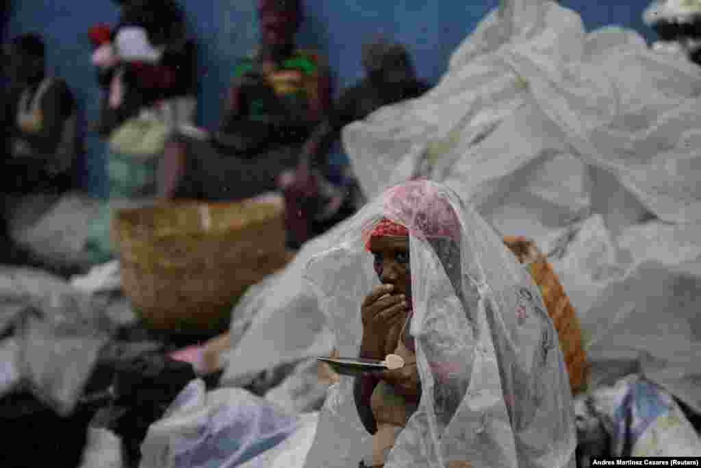 A woman protects herself from rain brought by Hurricane Irma as she eats lunch in a street of Cap-Haitien, Haiti, on September 7. (Reuters/Andres Martinez Casares)