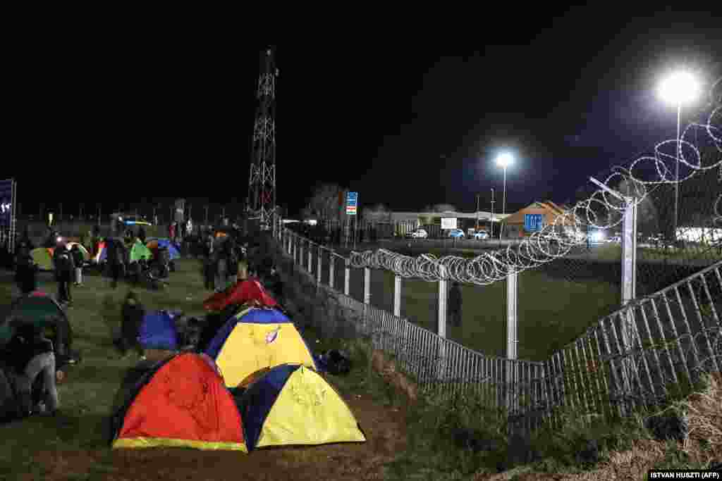 Migrants camp in tents next to the border fence.