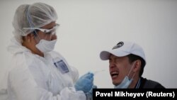 Медқызметкер коронавирустың бар-жоғын анықтайтынн мобильді тестілеу орталығында ПТР талдауына қажет сілекей үлгісін алып жатыр. Алматы, 17 маусым 2020 жыл.
