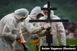 Gravediggers wearing personal protective equipment bury a person who is believed to have died of COVID-19 in St. Petersburg earlier this year.