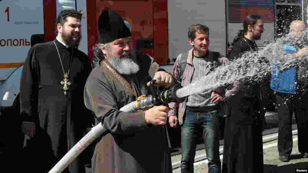 Священнослужители отрабатывают навыки тушения пожара во время учений МЧС в Симферополе, 4 апреля 2017 года