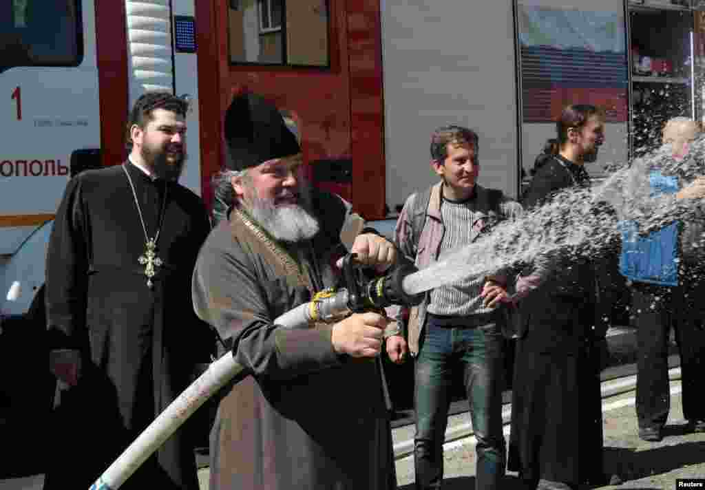 An Orthodox priest takes part in practical exercises on fire-extinguishing in Simferopol, Crimea, illegally annexed by Russia in 2014. (Reuters/Pavel Rebrov)