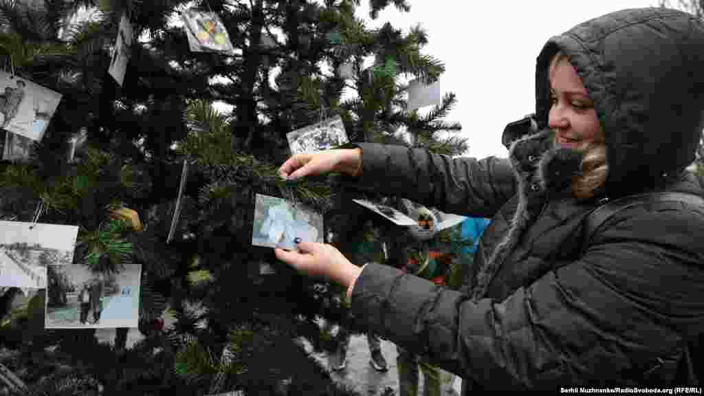Дарья Дударенко прикрепляет семейное фото на установленной новогодней елке. Она родилась в Припяти в январе 1986 года