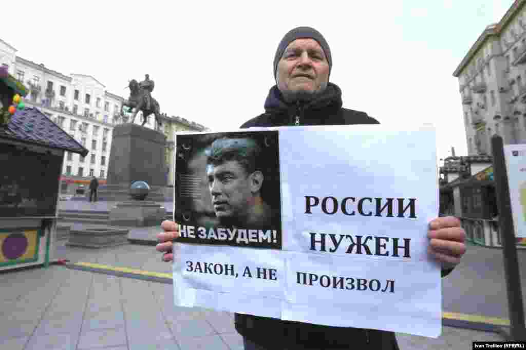 Қастандықпен өлтірілген оппозициялық саясаткер Борис Немцовтың суреті мен &quot;Ресейге озбырлық емес, заң керек&quot; деген жазу ұстап наразылық пикетінде тұрған ер адам. Мәскеу, 19 сәуір 2015 жыл.