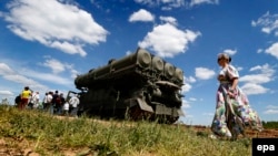 A woman walks past a rocket launcher during the International Military-Technical Forum ARMY-2015 in the Russian military Patriot park in Kubinka, outside Moscow.