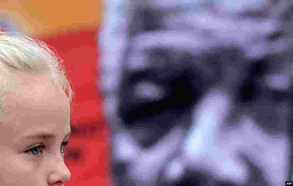 A young girl cries near a Nelson Mandela portrait outside the Medi Clinic Heart hospital where the antiapartheid icon and former South African president lay in critical condition in Pretoria. (AFP/Filippo Monteforte)