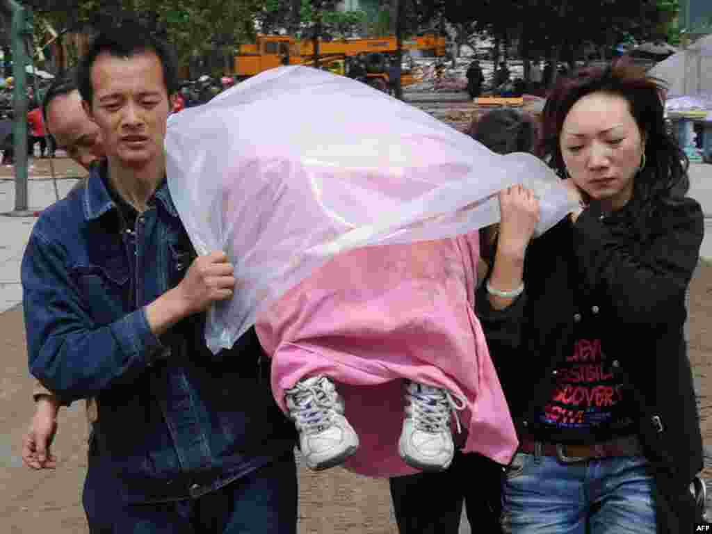 70 000 die in Chinese earthquake. - A Chinese couple carries the body of their primary school aged child away from the school (behind) that collapsed after a 7.8 magnitude earthquake hit the town of Hanwang in Sichuan Province, on May 14, 2008. China's biggest earthquake for a generation left tens of thousands dead, missing or buried under the rubble of crushed communities, plunging the nation into an all-out aid effort. Troops and rescue teams struggled by air, land and water to reach areas of southwestern China stricken by the huge quake that demolished schools, homes and factories. 