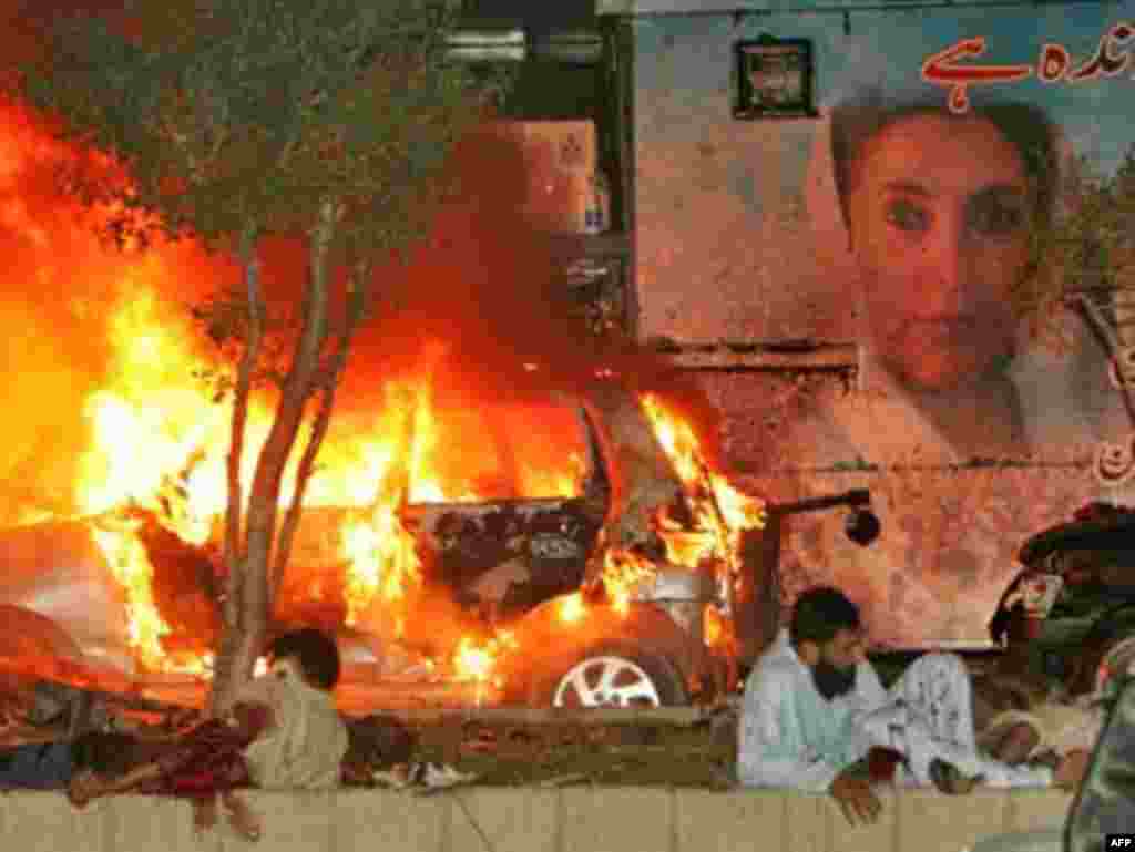 Pakistan - Wounded Pakistani men wait for help on the site of a blast site near the convoy of former prime minister Benazir Bhutto in Karachi, 18Oct2007 - 18 жовтня 2007, Карачі: поранені чекають на медичну допомогу після вибуху під час параду з приводу повернення Беназір Бхутто до Пакистану. Щонайменше 100 осіб загинуло, більше ніж 150 було поранено внаслідок вибуху двох бомб.