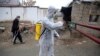 A volunteer in a protective suit sprays disinfectant outside a local police station to help curb the spread of coronavirus in the Afghan Kabul on March 23.