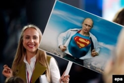A Russian journalist holds a placard depicting President Vladimir Putin as Superman prior to the press conference.