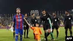 FILE: FC Barcelona Lionel Messi (L) holds the hands of Afghan boy Murtaza Ahmadi on the pitch before the start of a friendly football match against Saudi Arabia's Al-Ahli FC in Doha (December 2016).