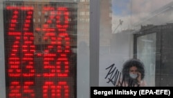 RUSSIA -- A woman leaves an exchange office with an electronic panel displaying currency exchange rates for U.S. dollar and euro against Russian ruble in Moscow, March 20, 2020