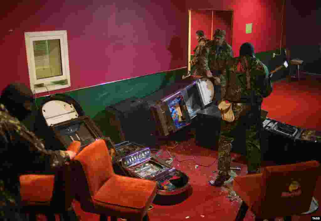Pro-Russia militia men destroy gambling machines in one of the gaming clubs in Slovyansk, Ukraine, on May 12. (ITAR-TASS/Mikhail Pochuyev)
