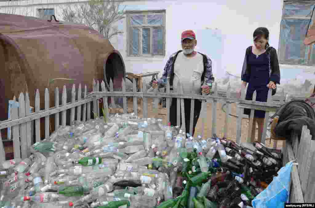 Зарип Нысанбеков стоит у груды бутылок, которые собирает для следующей постройки. Говорит, что для строительства приюта понадобится 18 тысяч бутылок.