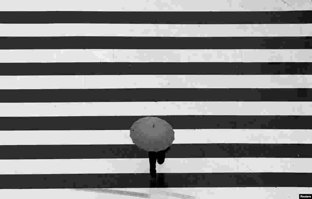 A man holding an umbrella crosses a street at a business district in Tokyo. (Reuters/Yuya Shino)