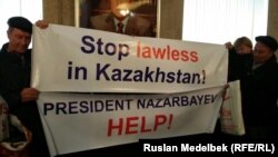 Сот шешімдеріне наразы тұрғындар "Нұр Отан" партиясы кеңсесінің ішінде плакат ұстап тұр. Алматы, 30 наурыз 2017 жыл.