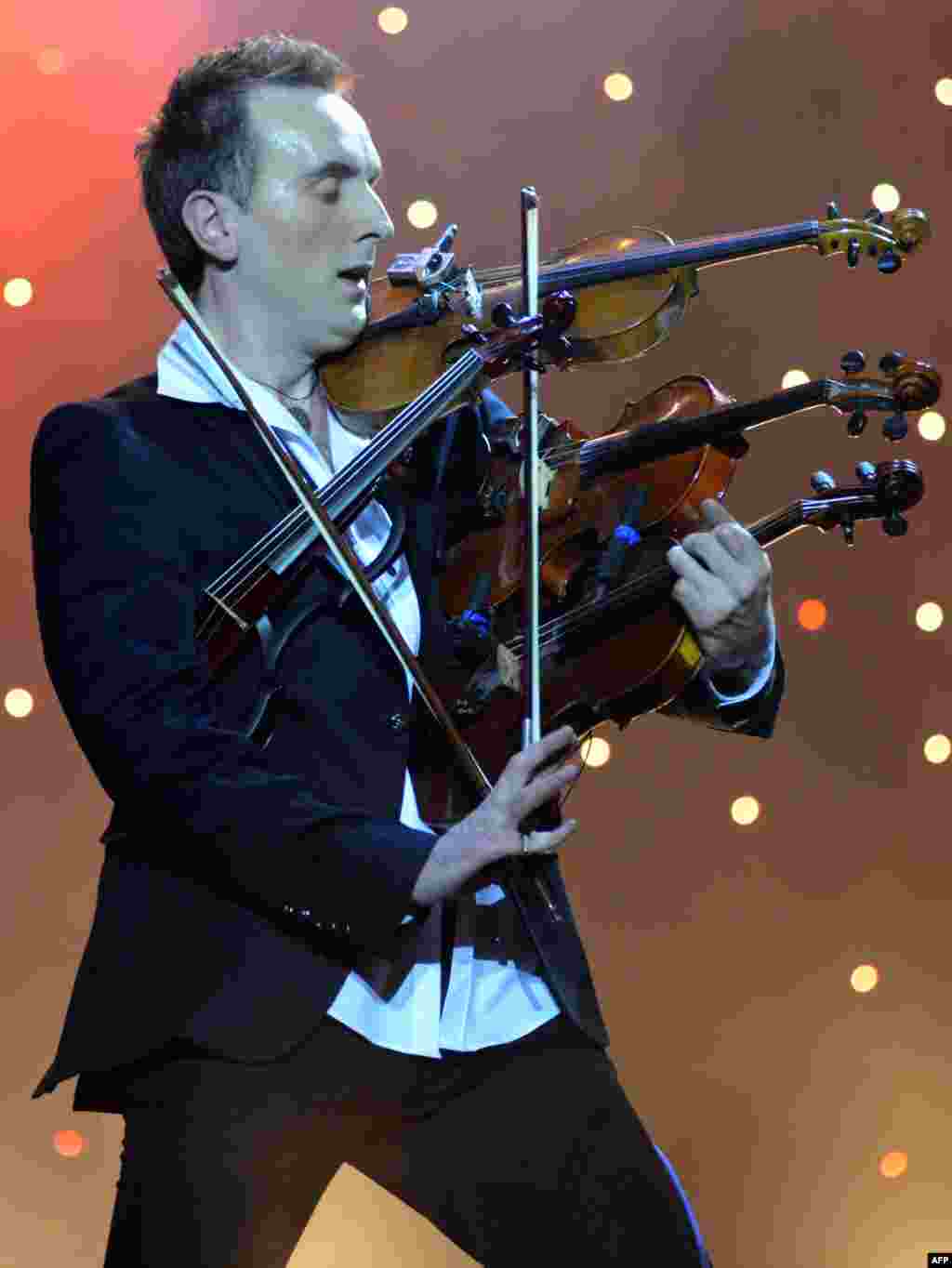 Ukrainian virtuoso Oleksandr Bozhyk plays four violins at the same time as he performs ''Requiem For A Dream" by Clint Mansell during a solo concert in the western Ukrainian city of Lviv. (AFP/Yuriy Dyachyshyn)