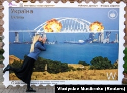 Твір мистецтва у формі великої марки, на якій зображено Кримський міст у вогні. Центр Києва, 8 жовтні 2022 року