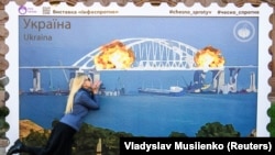 Увеличенная копия марки, на которой изображен Керченский (Крымский мост) в огне. Центр Киева, Украина, 8 октября 2022 года