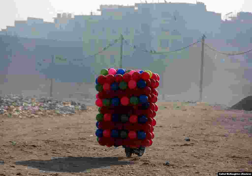 A man carries children's colored plastic balls on his motorcycle in Delhi. (Reuters/Cathal McNaughton)