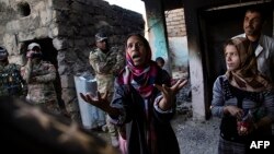 A photo by Ali Arkady taken on November 7, 2016, shows a woman speaking with an ERD intelligence officer, after her house was bombed by Iraqi air strikes and her brother kidnapped by Islamic State, in the village of Qabr al-Abd village, near Mosul.