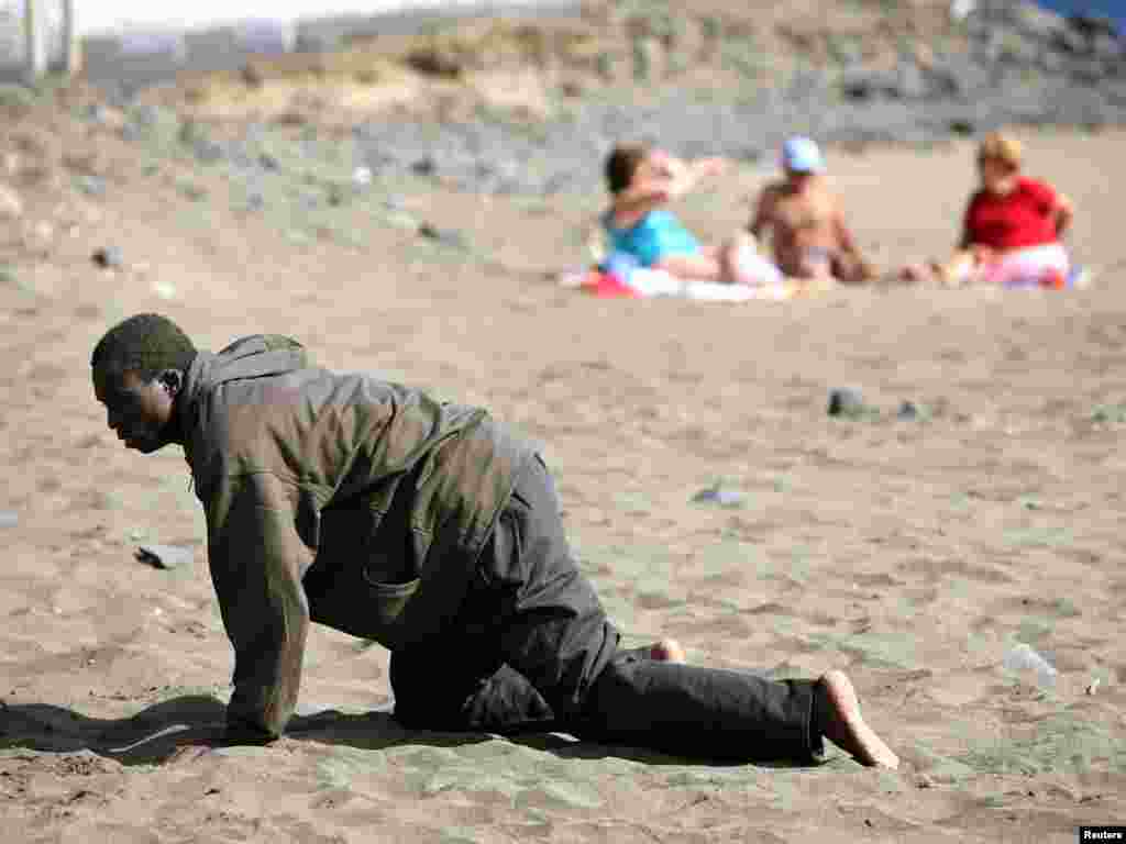 A would-be immigrant crawls after his arrival on a makeshift boat on the Gran Tarajal beach in Spain's Canary Island, May 5, 2006. Some 38 would-be immigrants arrived at the beach on a makeshift boat and some 39 were intercepted on a makeshift boat off Spain's Canary Island of Fuerteventura on their way to reach European soil from Africa. REUTERS/Juan Medina